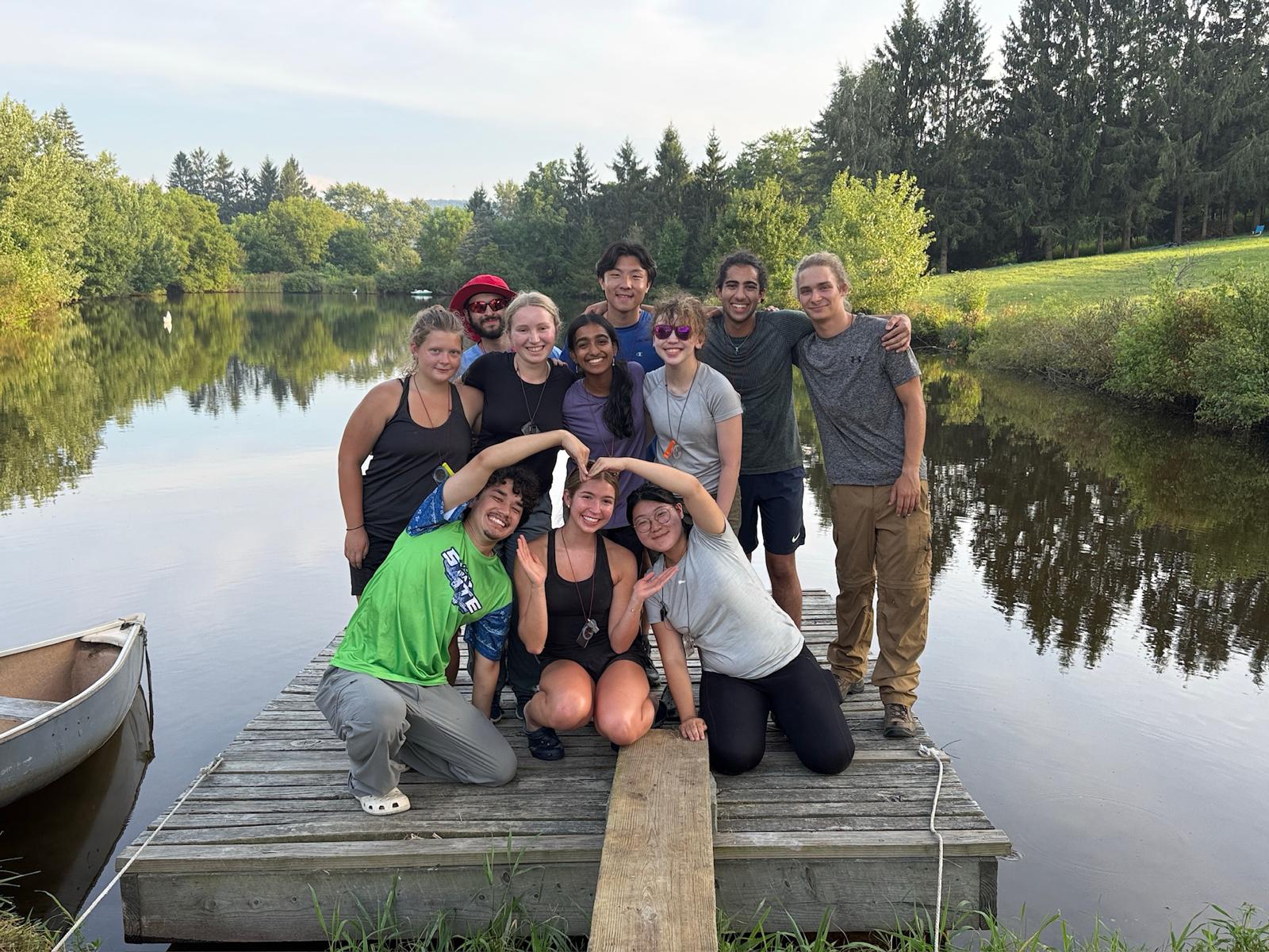 A group picture of Odyssey's 2025 Farm Trip! Pictured on Underhill Farm's dock, trip members and guide huddling with their arms around each other, smiling.