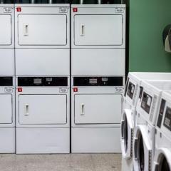 Two rows of dryers and three washing machines in a laundry room in Court-Kay-Bauer Hall