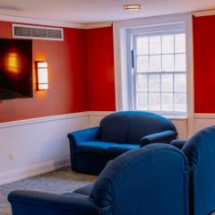 Lounge space in Clara Dickson Hall with red walls, three couches, a coffee table, and a television mounted on the wall