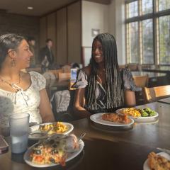 Two students smile at each other at a table with plates of food on it