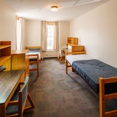 A bedroom with two twin beds, dressers, desks, and chairs.
