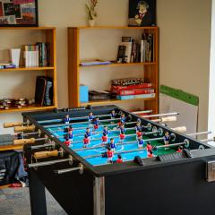 A foosball table and other games on shelves in a large lounge in JAM.