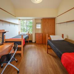A bedroom with two twin beds, desks, dressers, chairs, and dressers..
