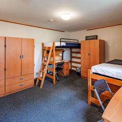 A bedroom with two twin beds, dressers, tables, and chair.