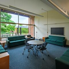 A lounge in JAM with couches, a table and chairs, and a tv.