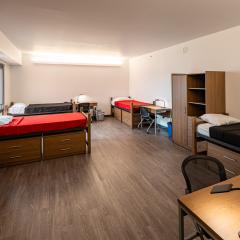 Quad room that has 4 beds, desks, and dressers