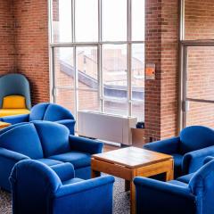 Blue chairs, small tables, and windows in a lounge in High Rise 5