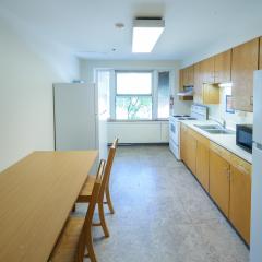 A communal kitchen with a table, chairs, fridge, microwave, sink, stove, oven, countertops and cabinets