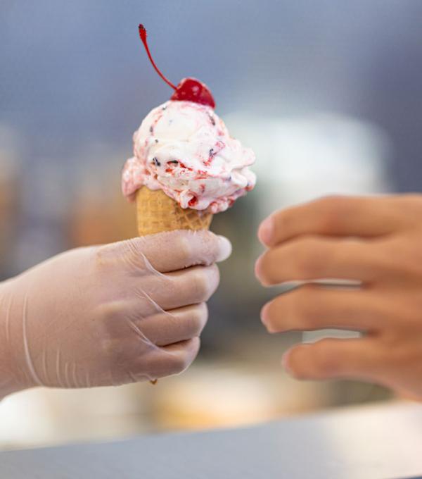 Food service worker handing ice cream cone to a customer