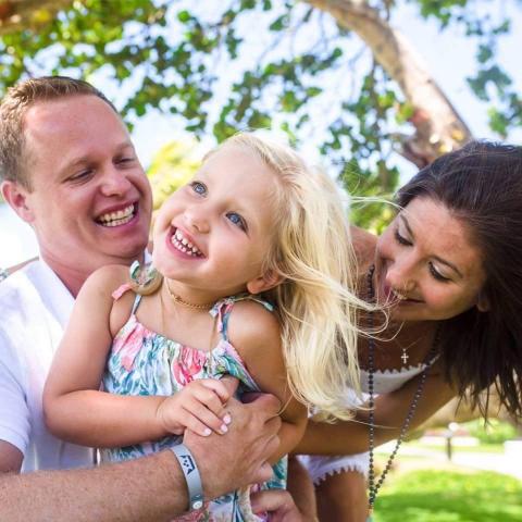 Two adults and a child with a tree in the background
