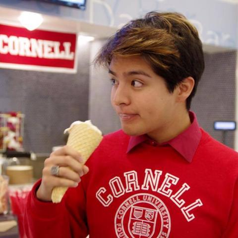 Student eating an ice cream cone wearing a Cornell sweatshirt