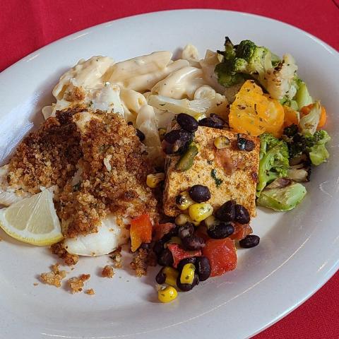 A plate of food including fish and vegetables on a tablecloth that matches Cornell's trademark red color