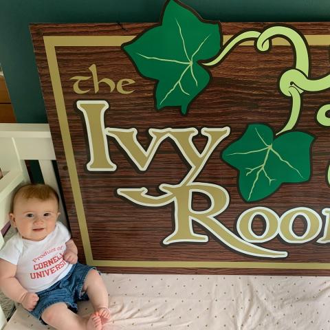A baby in front of a sign that says The Ivy Room