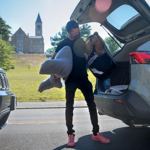 A student wearing a mask unloading a car to move in on opening weekend