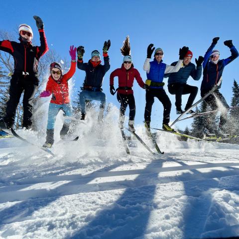 Members of the Cross-Country Skiing Club jump in the air.