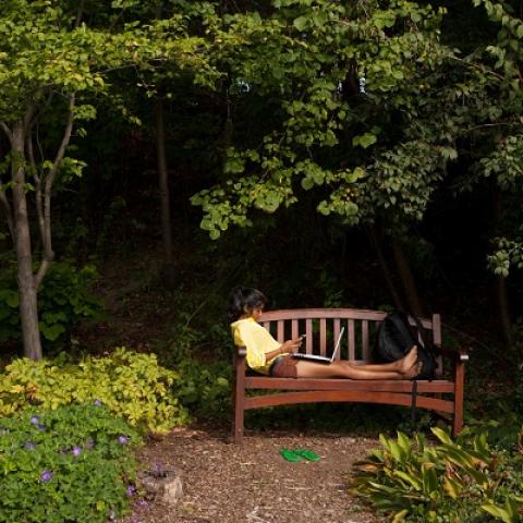 Student on bench with feet up surround by plants