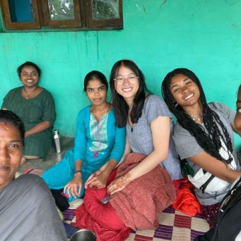 People sit on ground and smile at camera