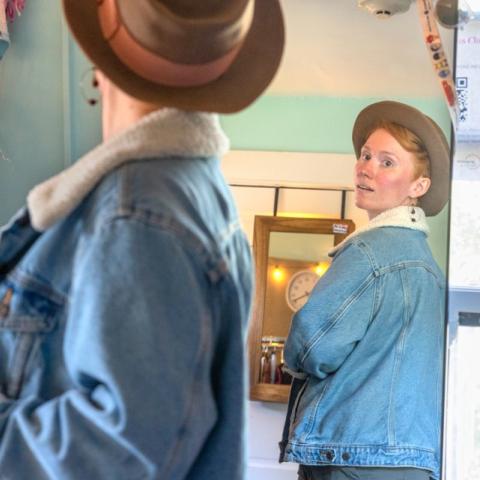 A person tries on a jacket in front of a mirror.