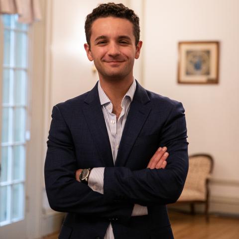 Andrew Lorenzen '22 stands smiling with his arms folded in a professional photo