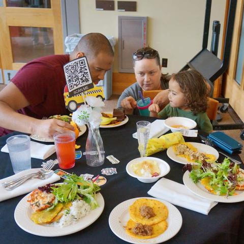 Adults and a child around a table with plates of food