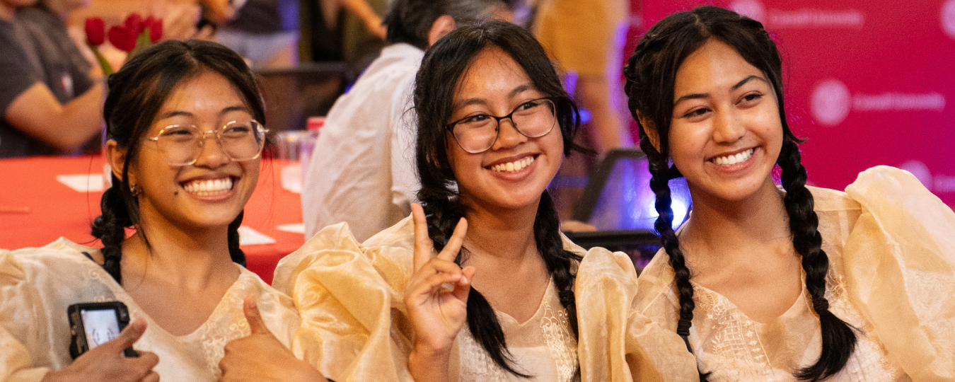 3 women smile in Asian dance outfits