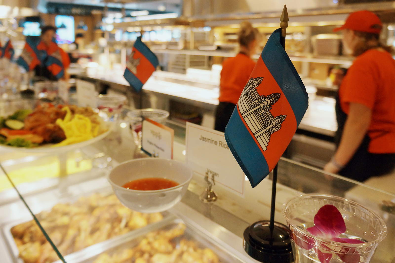 Small Cambodian flags sit on top of a counter with food serving containers below