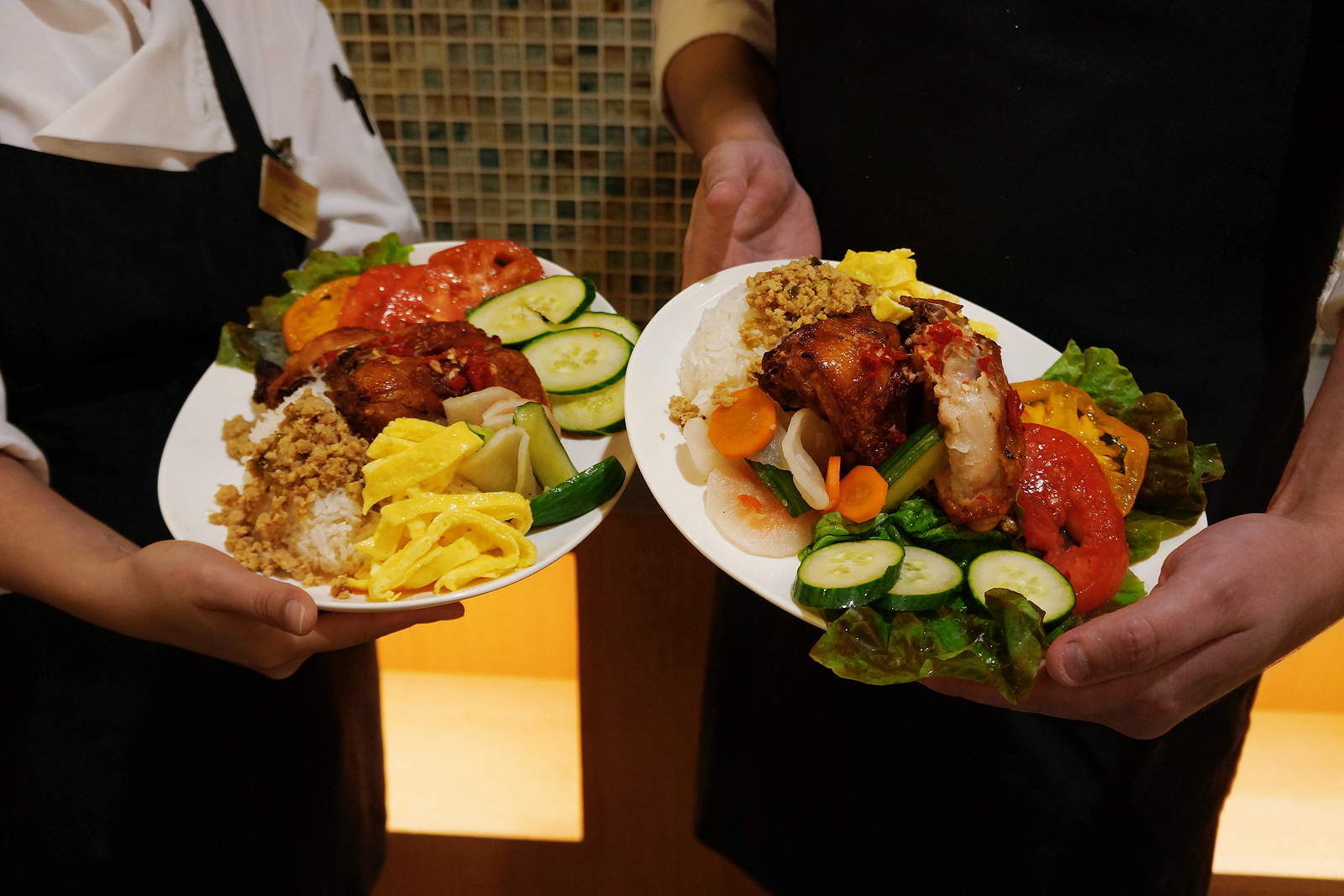 A closeup of two plates full of food being held by two people