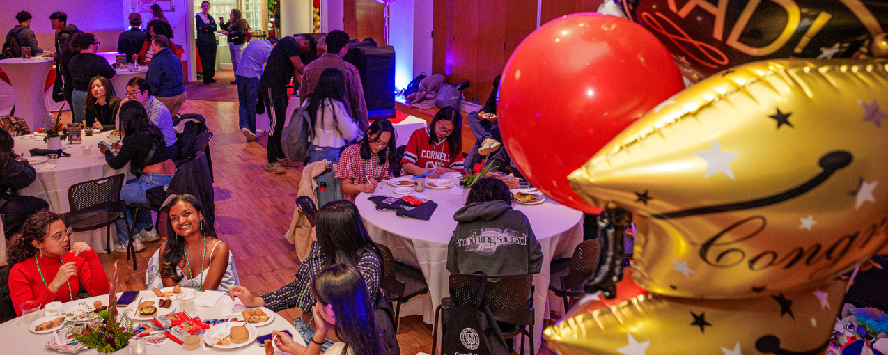 A room full of people sitting at tables, with balloons