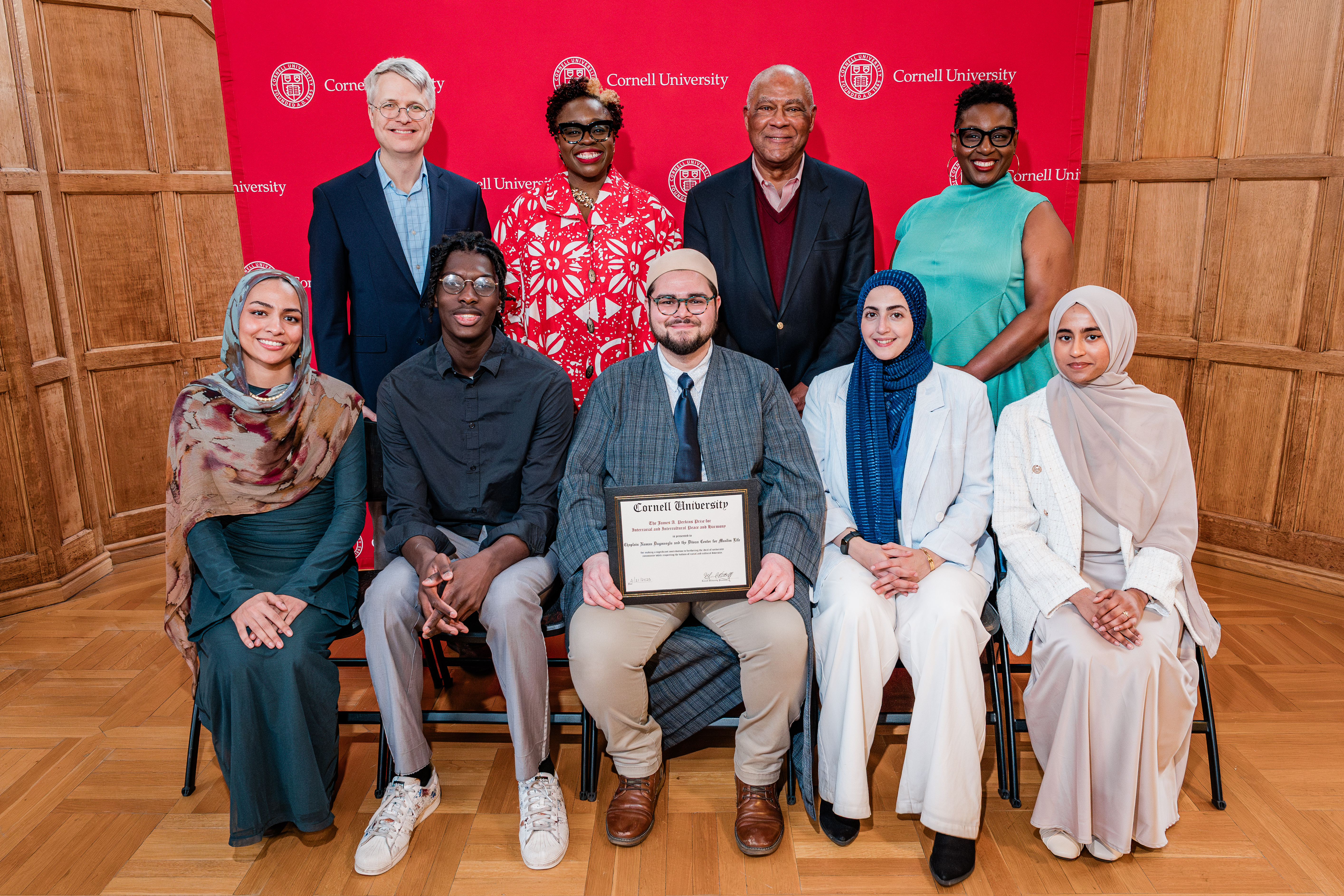 2025 award winners pose with Cornell leaders against a red backdrop.