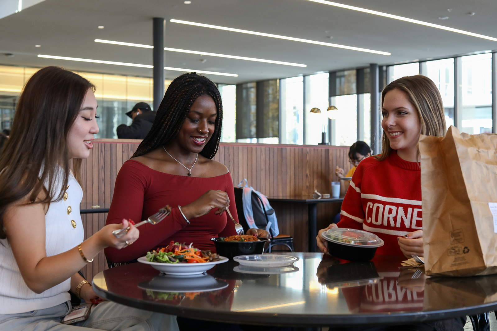 Three students eat in a dining room