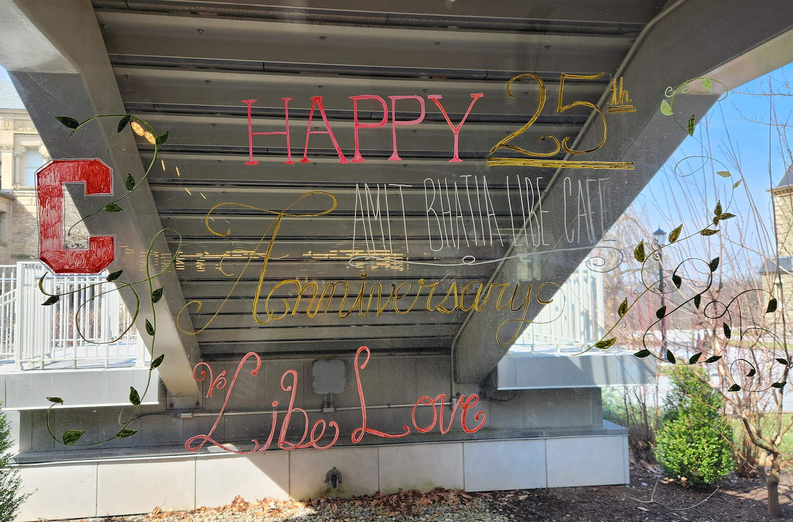 A window with outdoor stairs seen through it. Written on the glass is a happy 25th anniversary message and the words Libe Love