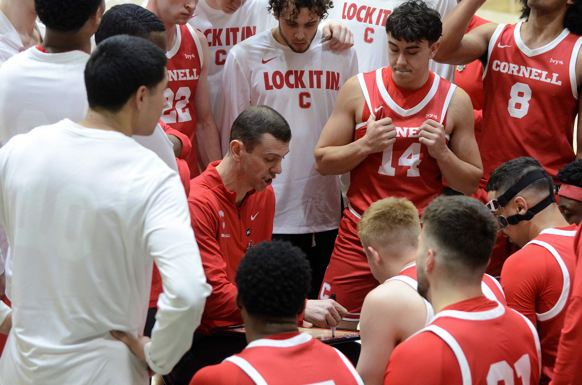 Players cluster around a coach on a basketball court