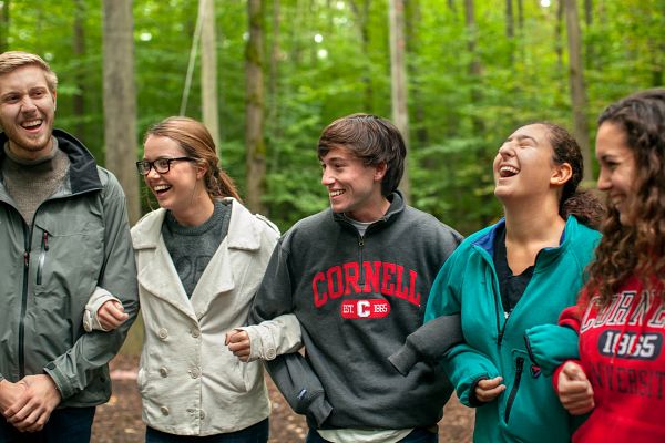 5 people laughing and linking arms outdoors in hoodies