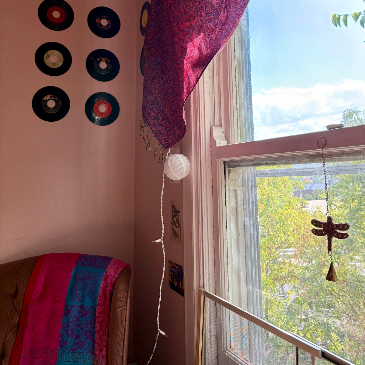 Chair in the corner of the room by a window with records on the wall for decoration