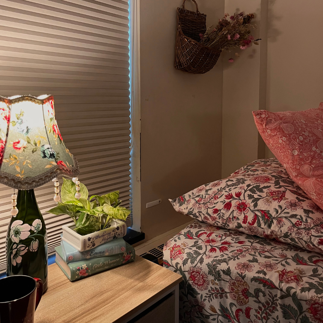 Bed with floral linens, nightstand with lamp