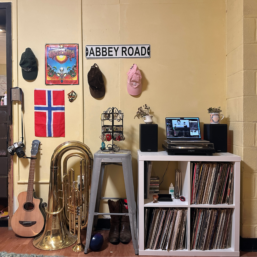 Guitar, tuba, stool, records on book shelves, abbey road sign