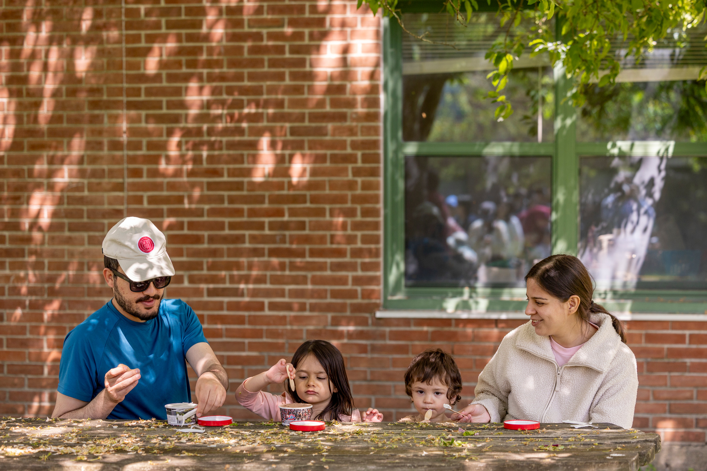 Student eating icecream sitting with their two kids at a picnic table