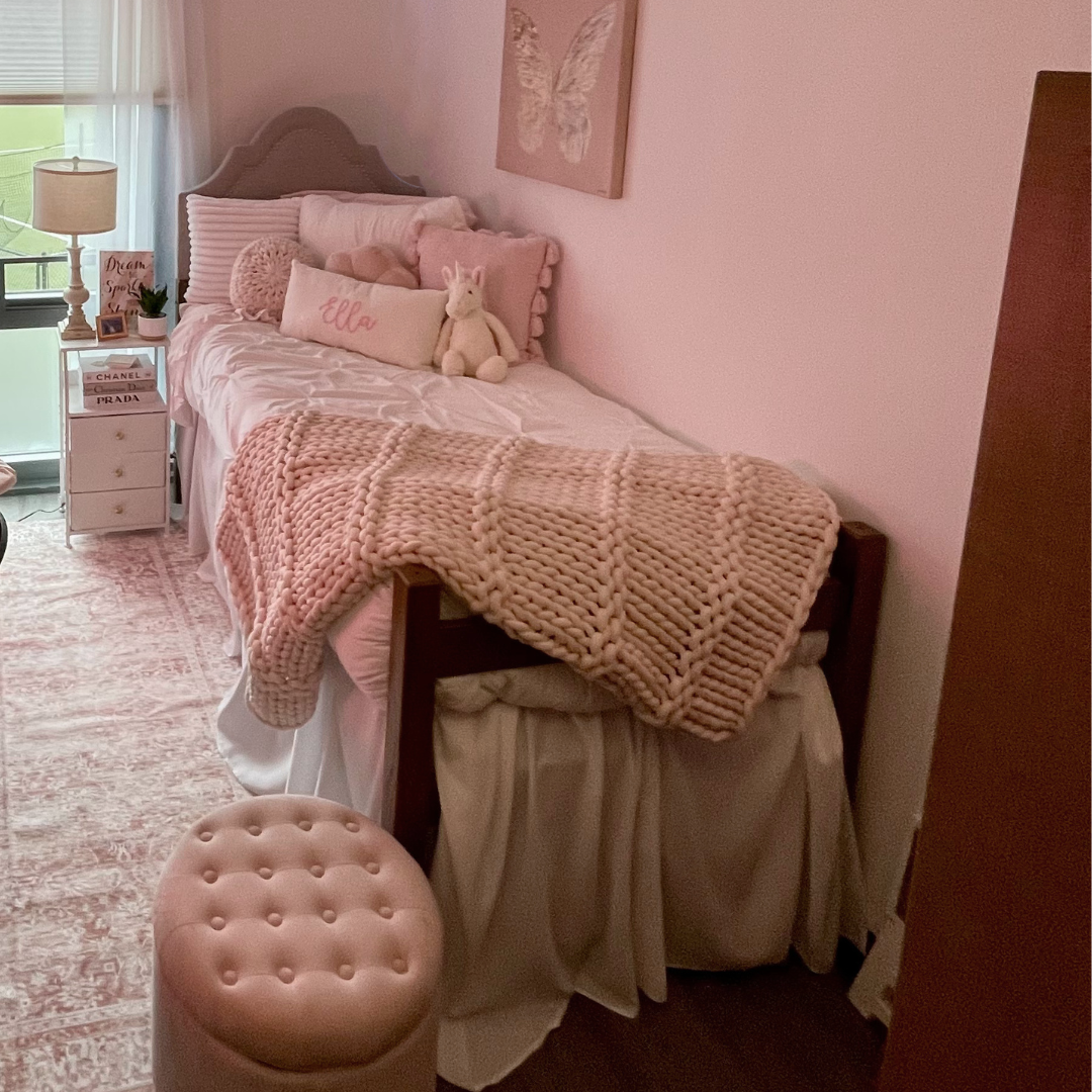 Student room picture bed with afghan, pillow with name, and nightstand