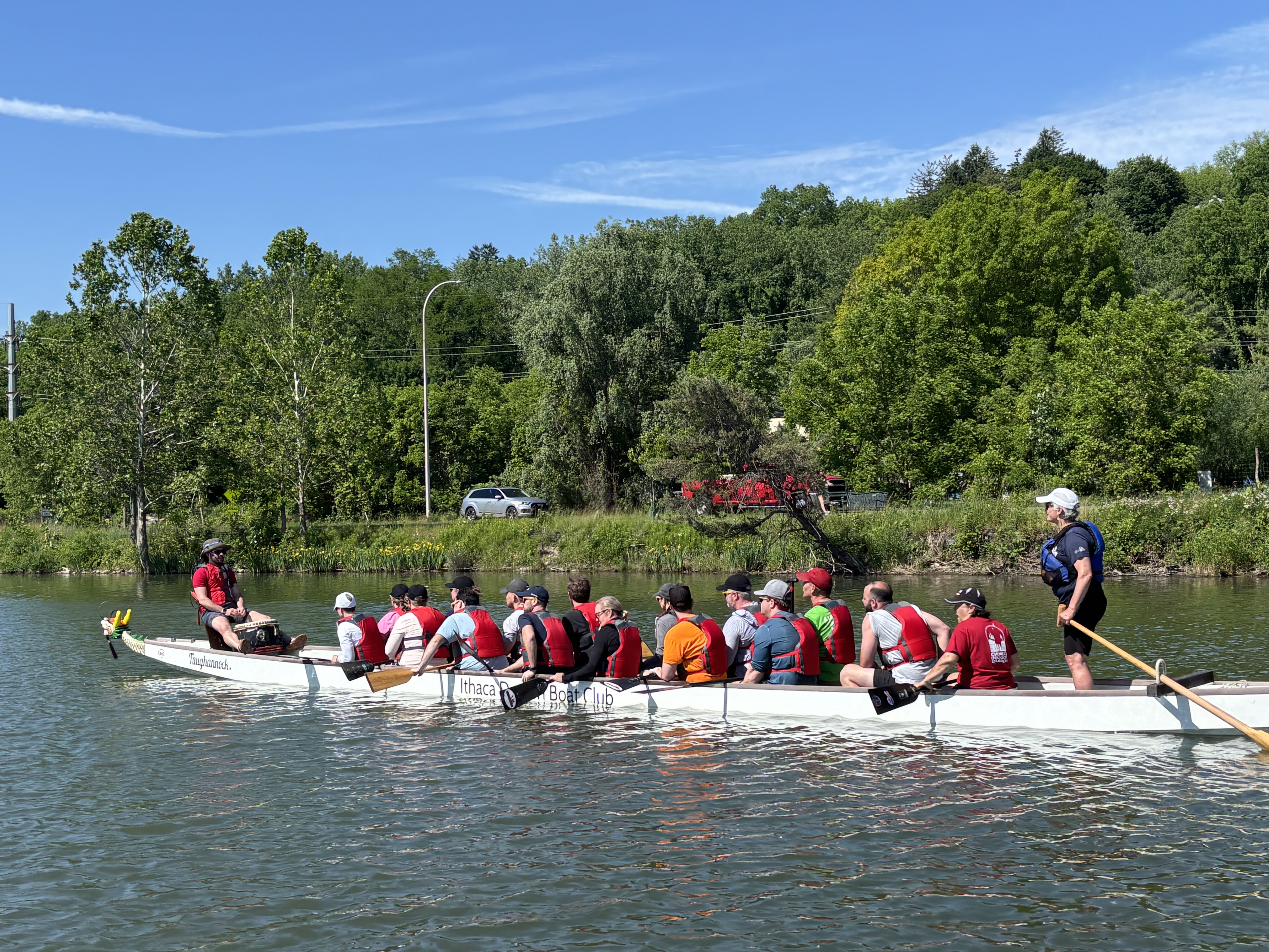 group of people in dragon boat with streerer standing at he stern