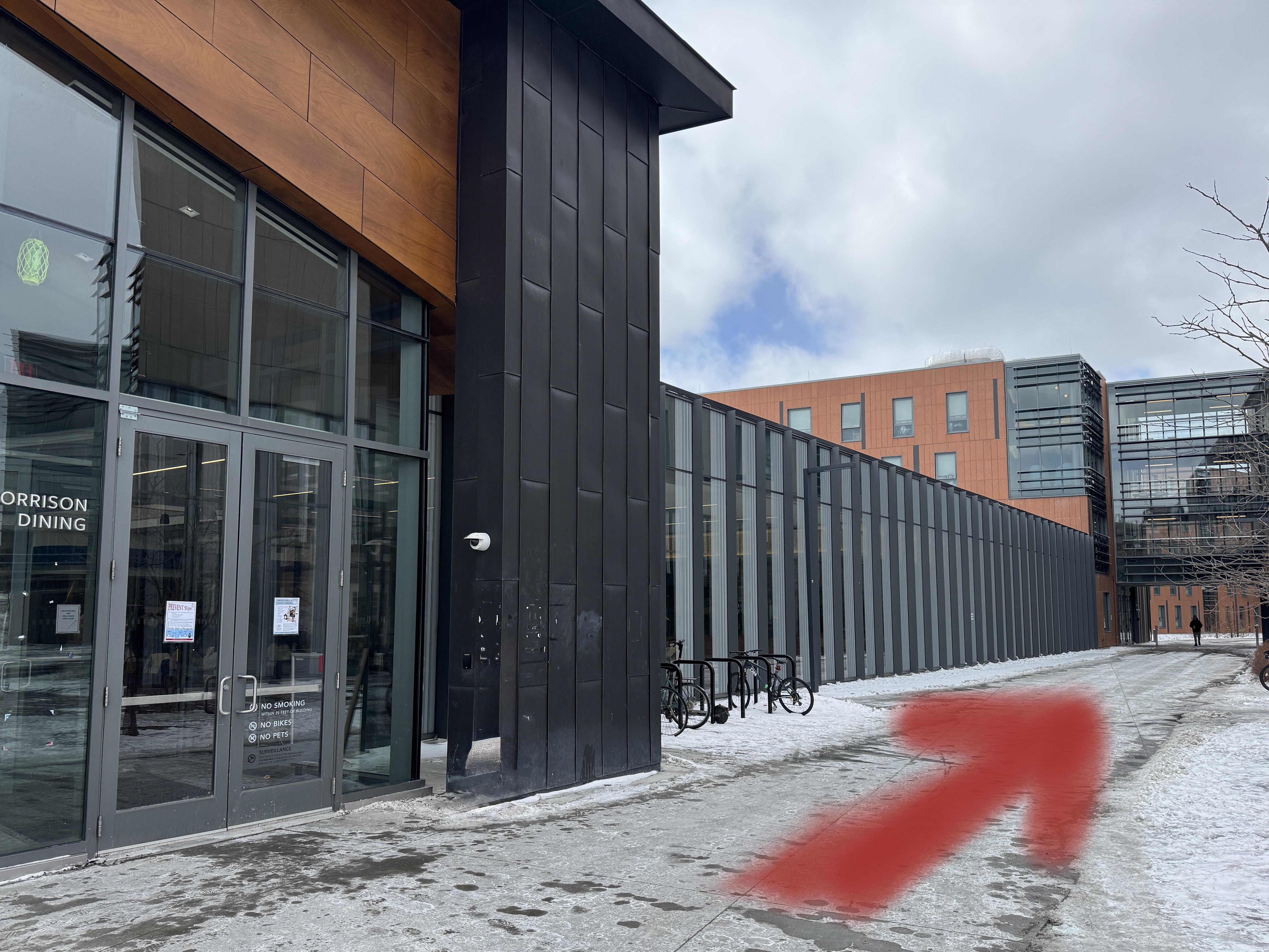 The outside of a building with an arrow pointing along the sidewalk