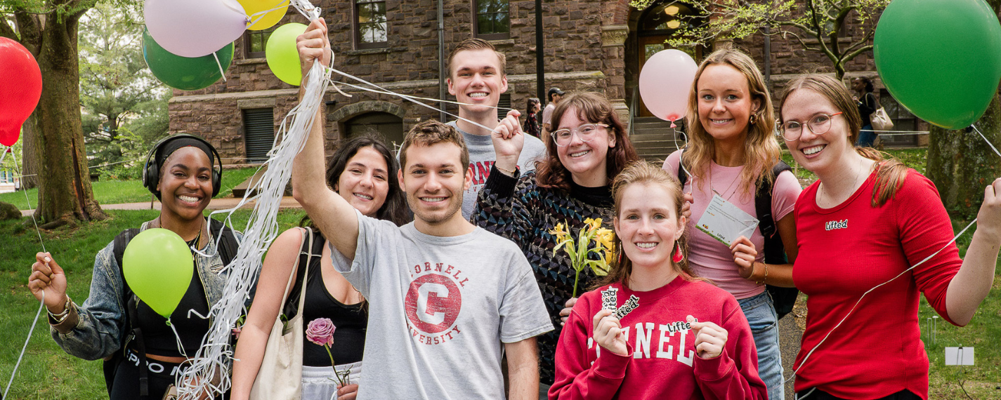 Students holding balloons on campus smiling