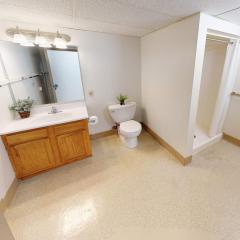 An apartment bathroom with sink, toilet, and stall shower