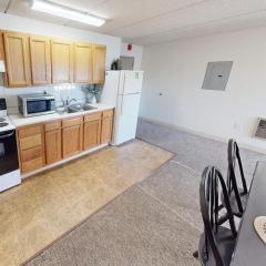 An apartment kitchen with corner of a dining table in the foreground