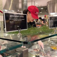 Two people wearing Cornell Dining caps serve food