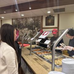 A person stands in front of a food serving line
