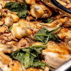 Serving dish filled with chicken and spinach in sauce