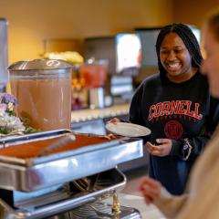 Students approaching a serving dish in a decorated dining room