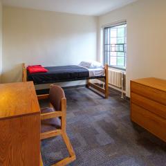 A bedroom in with a twin bed, dresser, table, and chair.