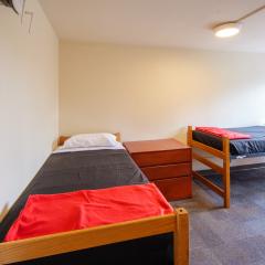 Double room with two twin beds, desks, chairs, lamps, dressers, and a window.