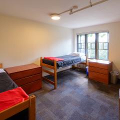Double room with two twin beds, desks, chairs, lamps, dressers, and a window.